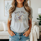 Gray t-shirt with "Born Wild" text above a colorful howling wolf and floral design.