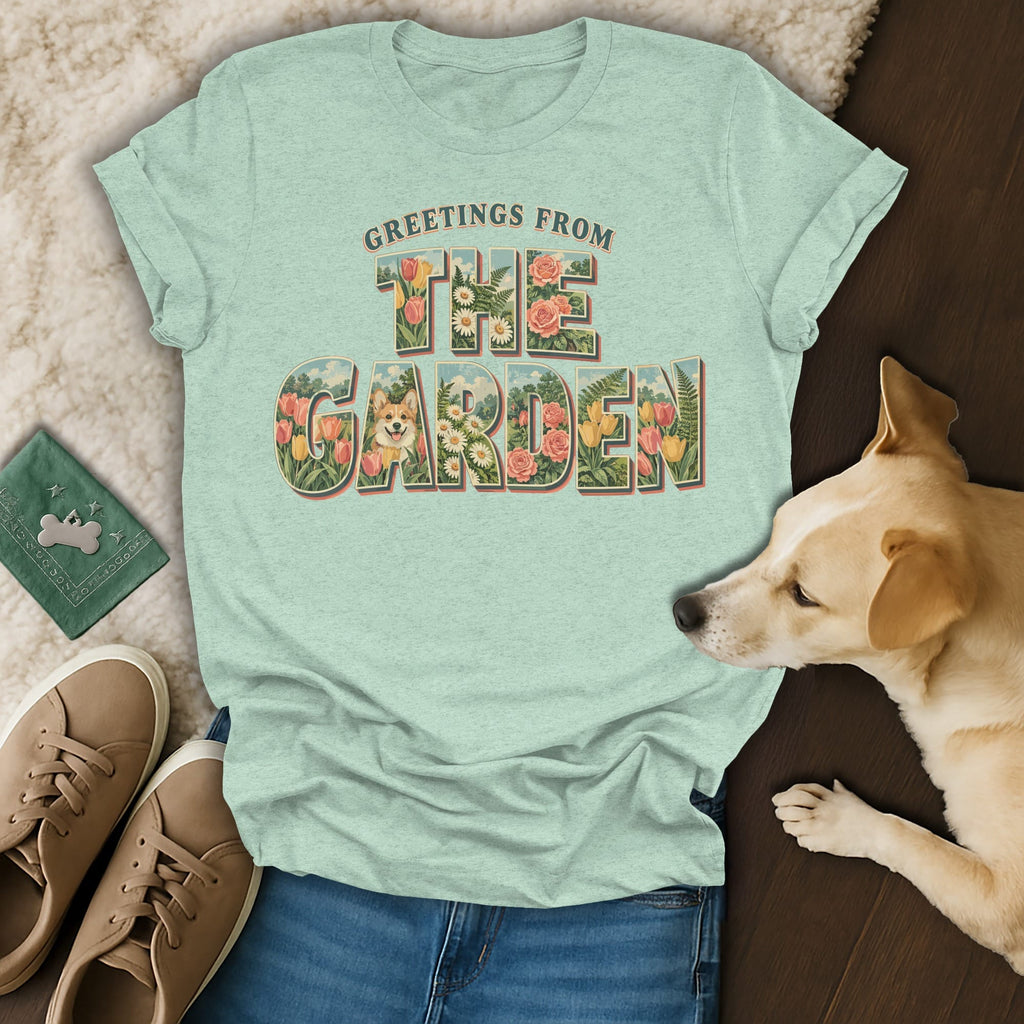 Light green t-shirt featuring floral text saying Greetings From The Garden, displayed with jeans, sneakers, and a dog.