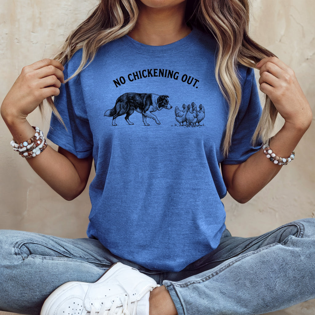 Blue t-shirt with black dog facing chickens and text "NO CHICKENING OUT."