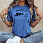 Blue t-shirt with black dog facing chickens and text "NO CHICKENING OUT."
