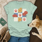 Light mint t-shirt with a grid design of red paw prints, red flowers, and yellow flowers.
