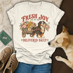Cream t-shirt featuring a graphic of a Bernese Mountain Dog pulling a flower cart, with the text Fresh Joy Delivered Daily.
