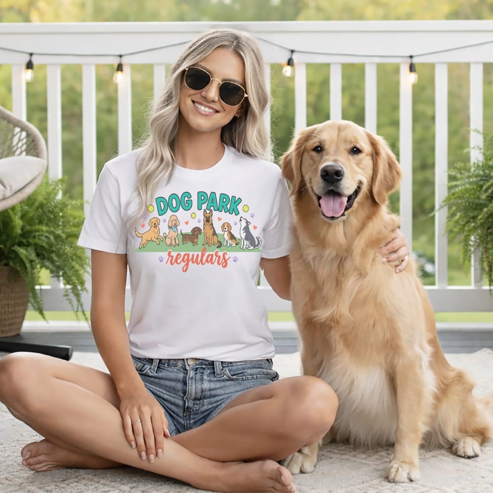Woman with golden retriever wears t-shirt with "Dog Park regulars" and cartoon dogs.