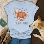 Light blue t-shirt with a golden retriever in a pumpkin, surrounded by autumn leaves.