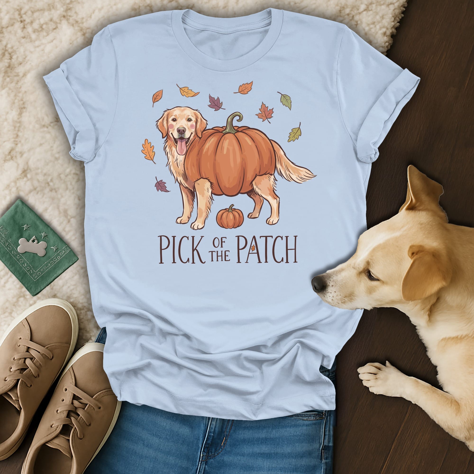 Light blue t-shirt with a golden retriever in a pumpkin, surrounded by autumn leaves.