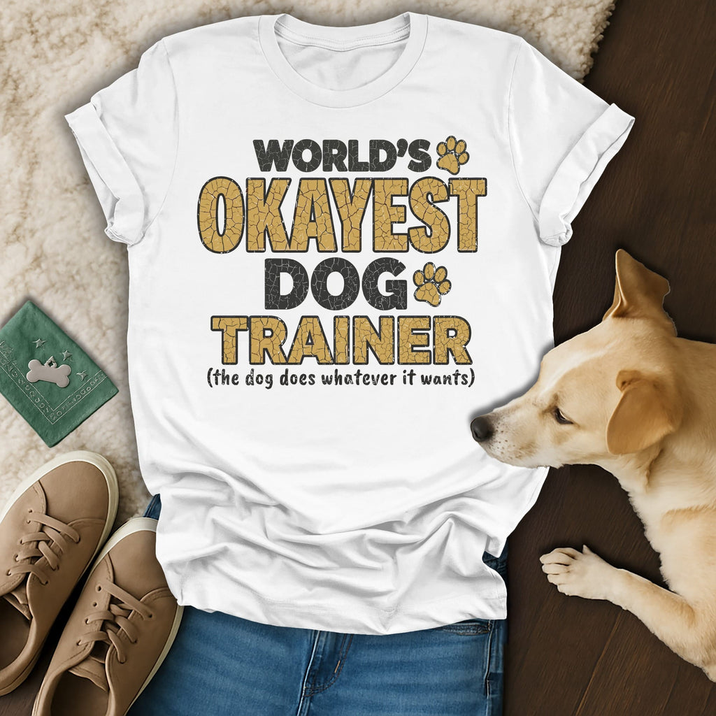 White t-shirt with "WORLD'S OKAYEST DOG TRAINER" text and paw prints.