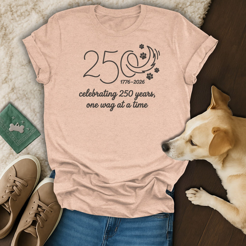 Peach t-shirt with "250 1776-2026 celebrating 250 years, one wag at a time" text and paw print design.