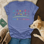 Purple t-shirt with colorful paw print flowers and "Paws & Smell the Roses" text.