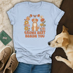 Light blue t-shirt featuring a cartoon dog and retro floral graphics with the text GROWS BEST BESIDE YOU.