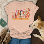 Peach t-shirt with cartoon dogs carrying bags and drinks in a line.