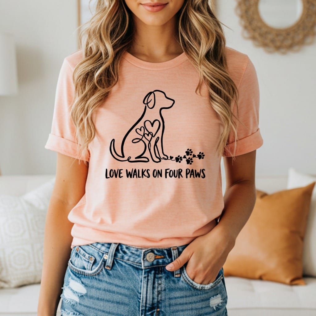 Peach t-shirt with dog silhouette, heart, paw prints, and text "LOVE WALKS ON FOUR PAWS".