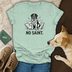 Mint green t-shirt with graphic of dog on pillow and text "NO SAINT."