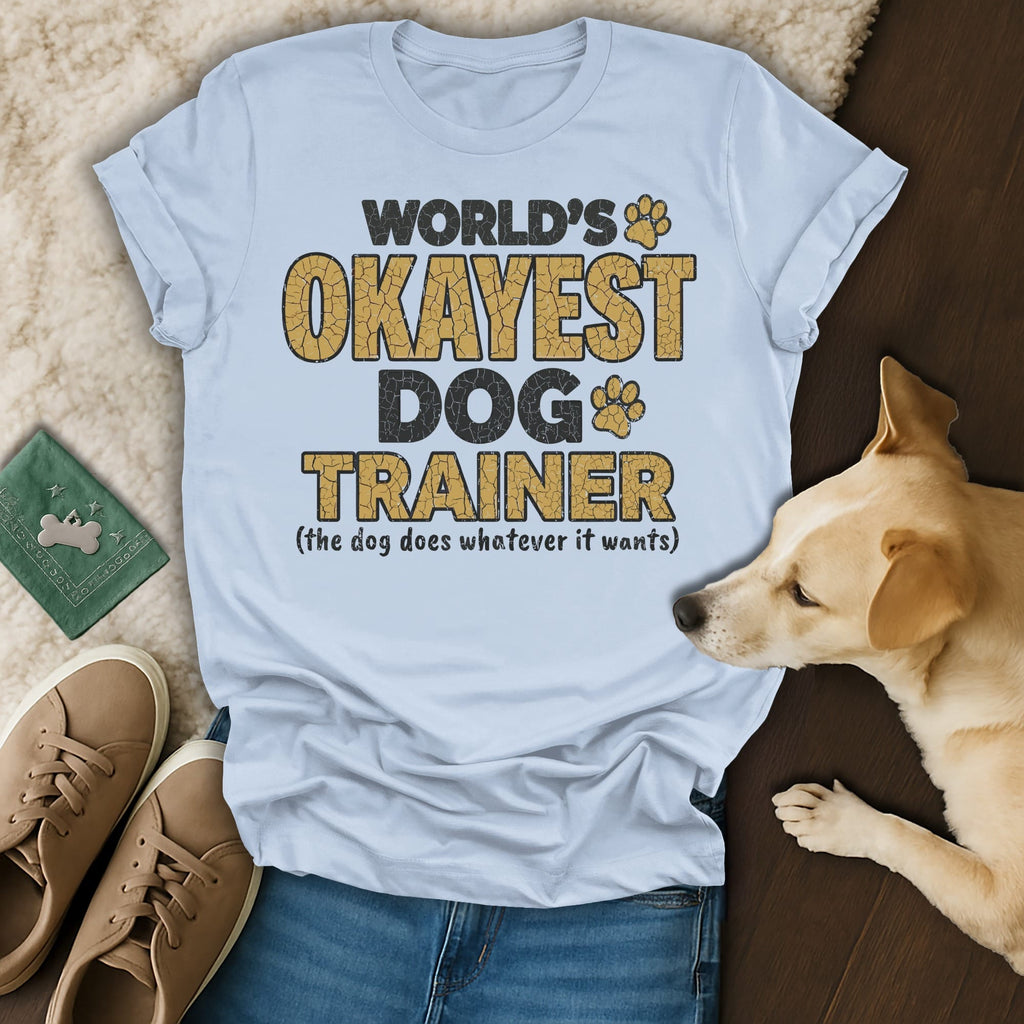 World's Okayest Dog Trainer shirt with dog paw prints and text.