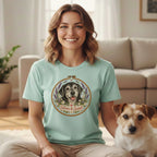 A woman wearing a light blue t-shirt featuring a dog graphic that reads "Silver & Sweet," seated next to a small dog.