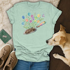 Light green t-shirt with colorful paw print floral design and gardening trowel.