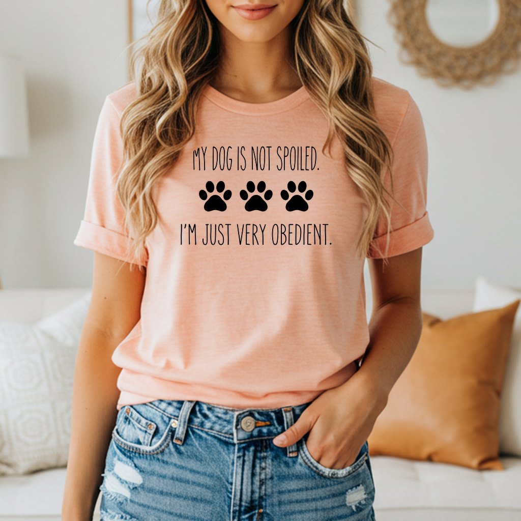 Peach t-shirt with black text and paw prints: "My dog is not spoiled. I'm just very obedient."