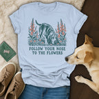 Light blue t-shirt featuring a dog sniffing flowers illustration with the text Follow Your Nose to the Flowers.