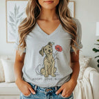A woman wearing a grey V-neck t-shirt featuring a cartoon dog holding a red poppy flower and the text ADOPT. LOVE. BLOOM.