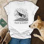 White t-shirt with a beagle jumping in fall leaves and the text "Leaf Me Alone".