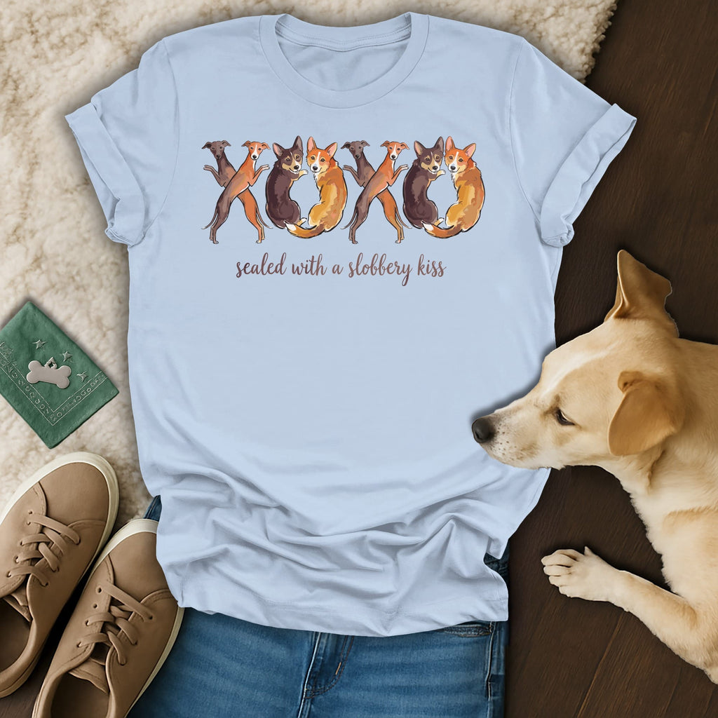 Light blue t-shirt with watercolor dogs forming XOXO and text "sealed with a slobbery kiss".