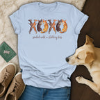 Light blue t-shirt with watercolor dogs forming XOXO and text "sealed with a slobbery kiss".