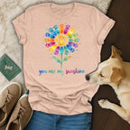 Peach t-shirt with rainbow paw print flower and "you are my sunshine" text.