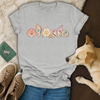 A grey crewneck t-shirt featuring a seashell graphic with paw prints, surrounded by shoes, a dog, and a passport.