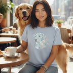 Woman wearing light blue t-shirt with geometric dog graphic and flowers, sitting with golden retriever.