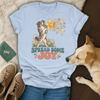 Light blue t-shirt featuring an Australian Shepherd graphic and the text "SPREAD SOME JOY," arranged with jeans, shoes, and a real dog.