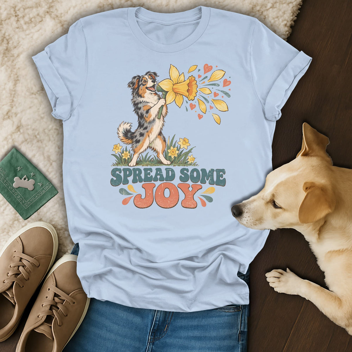 Light blue t-shirt featuring an Australian Shepherd graphic and the text "SPREAD SOME JOY," arranged with jeans, shoes, and a real dog.