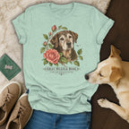 Mint green t-shirt featuring a botanical illustration of an older dog and roses, surrounded by casual accessories and a real dog.