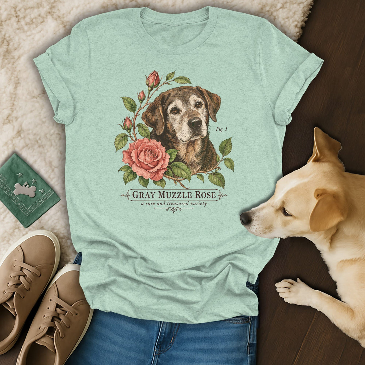 Mint green t-shirt featuring a botanical illustration of an older dog and roses, surrounded by casual accessories and a real dog.