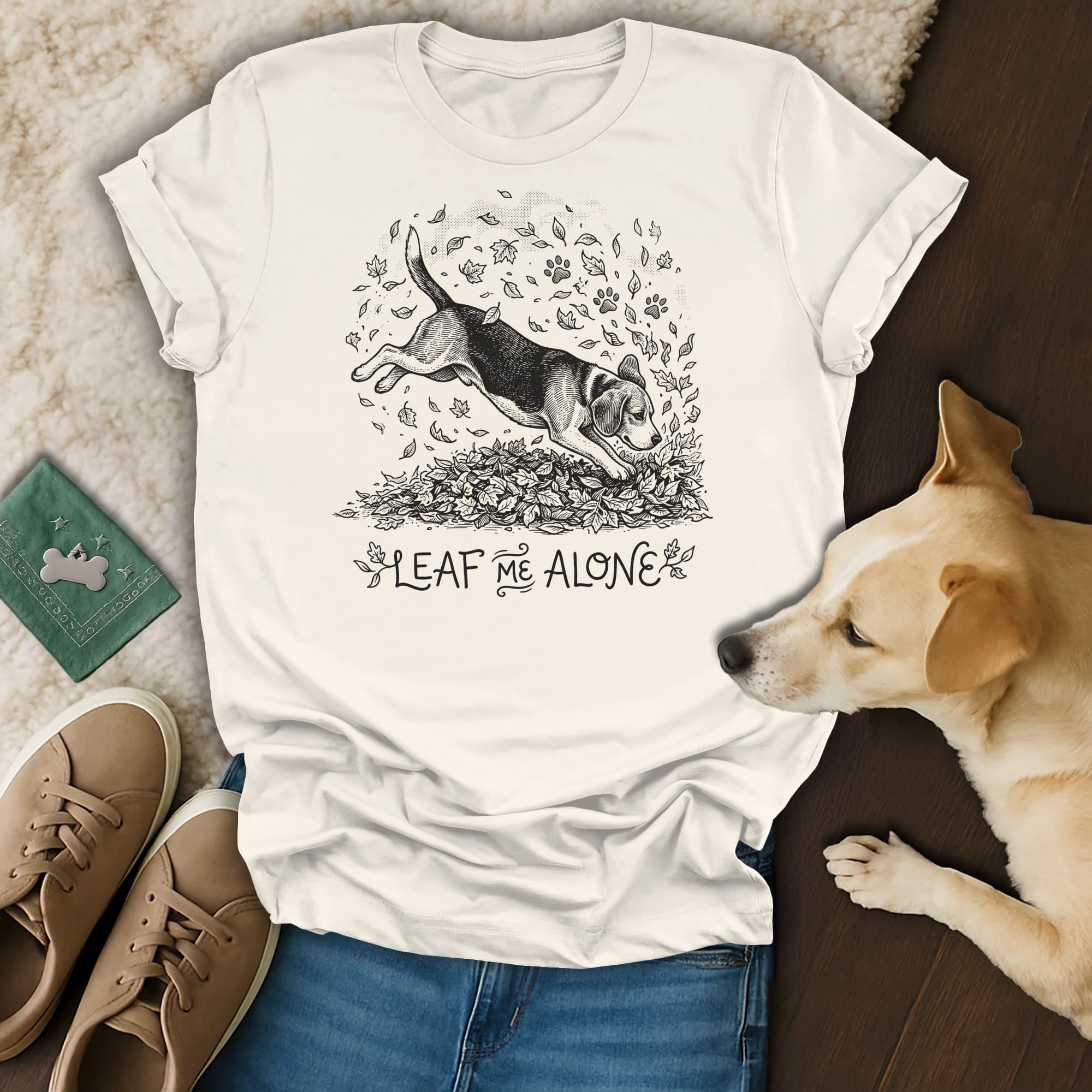 T-shirt graphic of a beagle jumping through fall leaves with the text "LEAF ME ALONE".