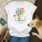 White t-shirt with watercolor print of a boot filled with colorful paw prints and flowers.