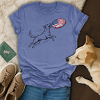Dog jumping to catch American flag rugby ball on blue t-shirt.