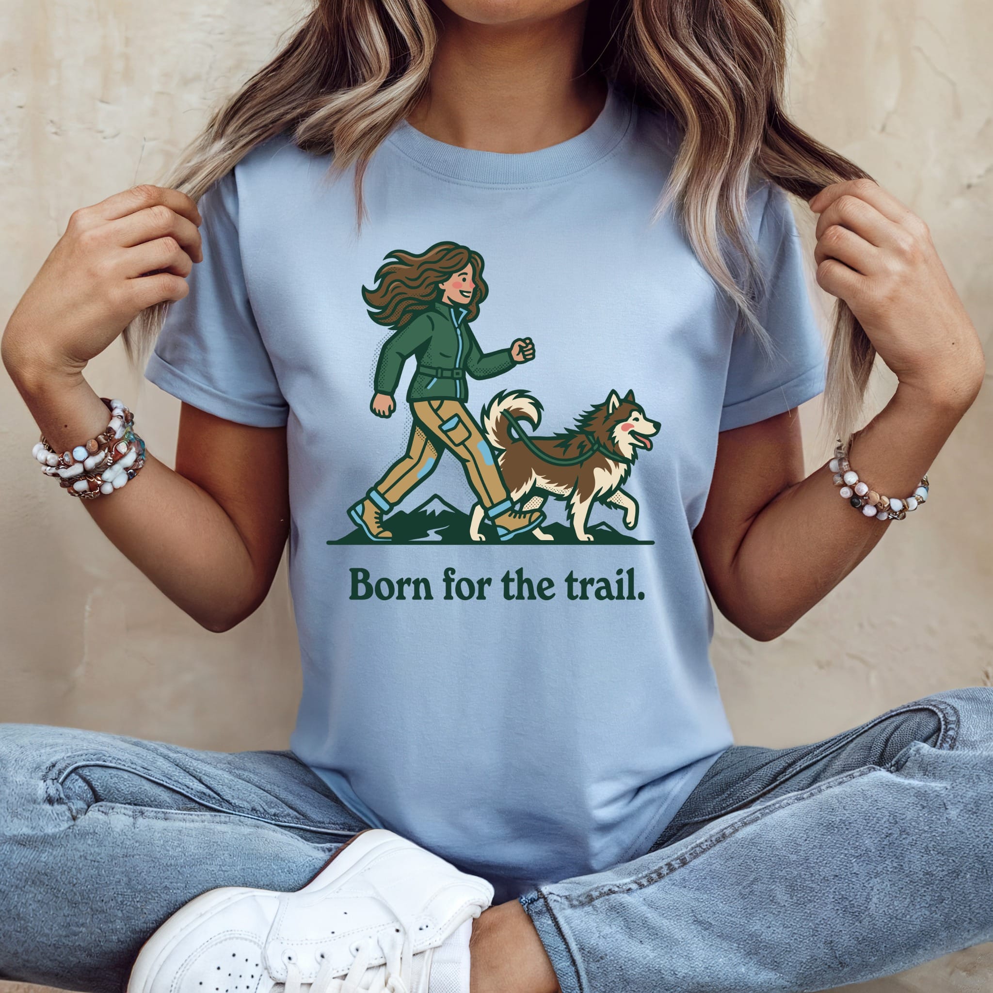 Light blue t-shirt with a woman walking a husky, text reads "Born for the trail."
