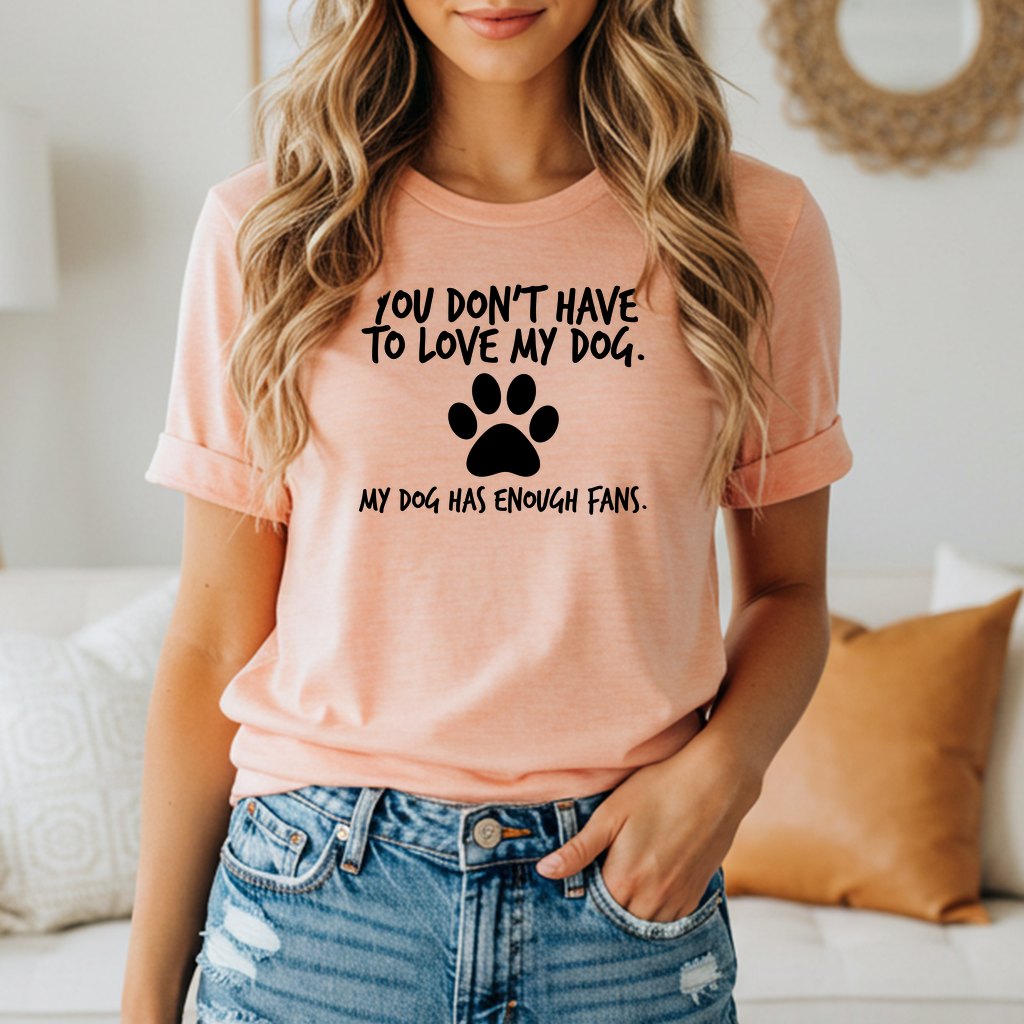 Peach t-shirt with black text: "YOU DON'T HAVE TO LOVE MY DOG. MY DOG HAS ENOUGH FANS."