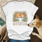 White v-neck t-shirt featuring a graphic of a sleeping golden retriever on a bench with flowers and text.
