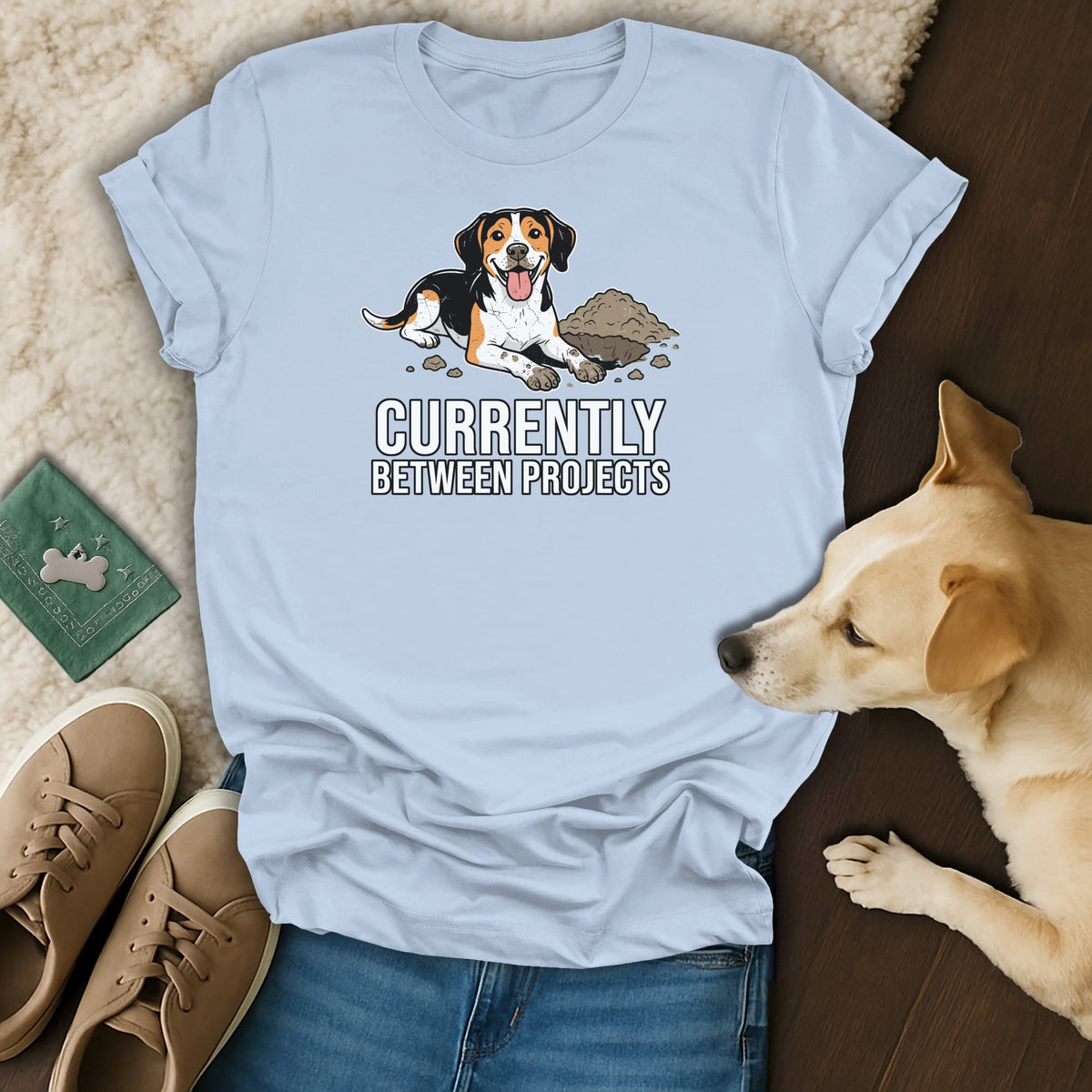 Light blue t-shirt with a cartoon dog digging in dirt and text "CURRENTLY BETWEEN PROJECTS."