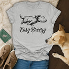 Gray t-shirt with "Easy Breezy" and a dog illustration, placed near dog accessories and shoes.