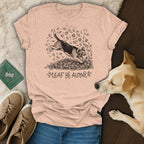 Peach t-shirt with beagle jumping in leaves graphic and "Leaf Me Alone" text.