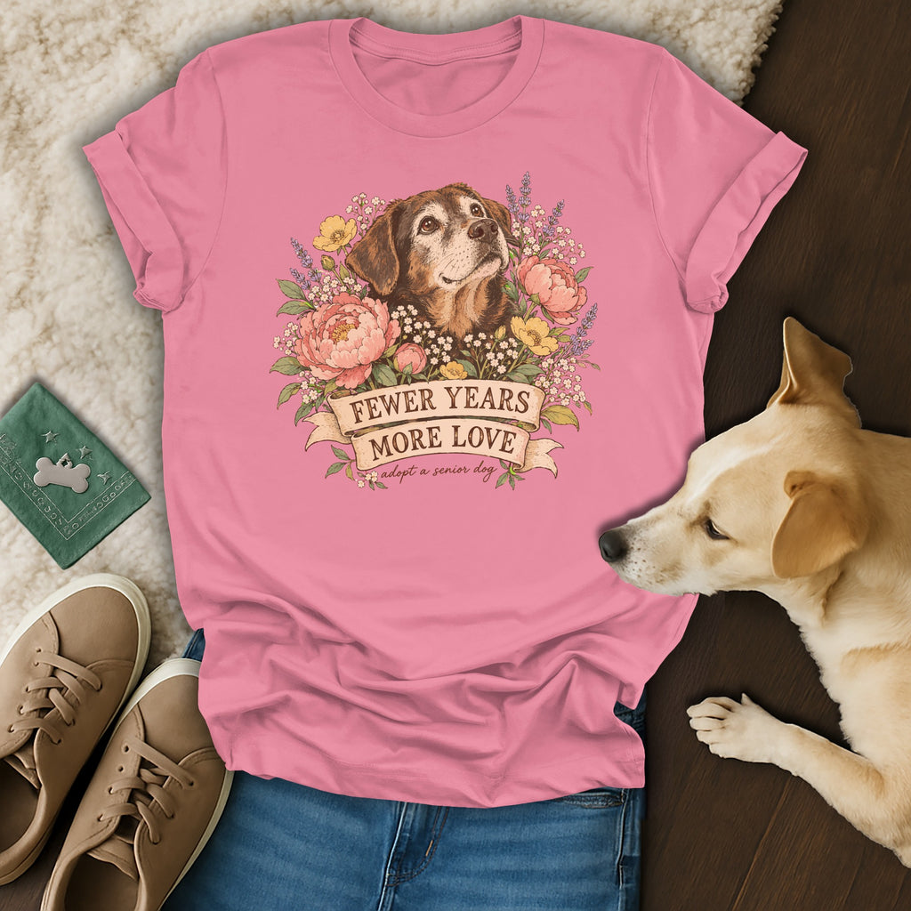 A pink crewneck t-shirt featuring an illustrated senior dog surrounded by flowers and the text Fewer Years More Love.