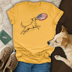 Dog jumping to catch an American flag football on a yellow t-shirt.
