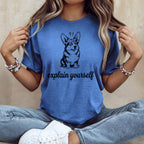 Blue t-shirt with black line drawing of a corgi and text "explain yourself".