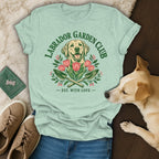 A light green t-shirt with a vintage Labrador Garden Club graphic featuring tulips, garden tools, and a smiling dog.