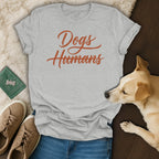 Grey t-shirt with "Dogs Humans" text, featuring a dog, shoes, and bandana.