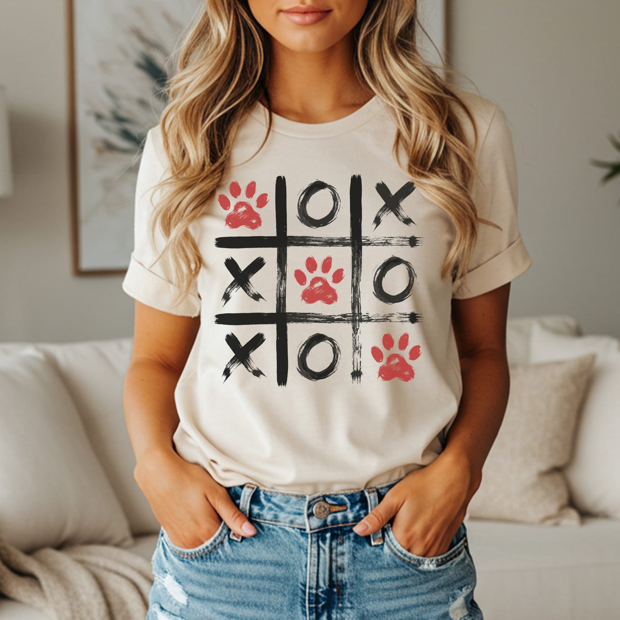 Cream t-shirt with a tic-tac-toe grid featuring red paw prints, black X's, and black O's.