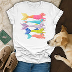 White t-shirt with cartoon dogs in mermaid tails in various colors.