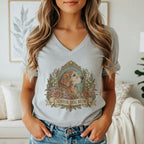 A woman wearing a gray V-neck t-shirt featuring a vintage illustration of a golden retriever surrounded by flowers and the text "SENIOR DOG MOM".