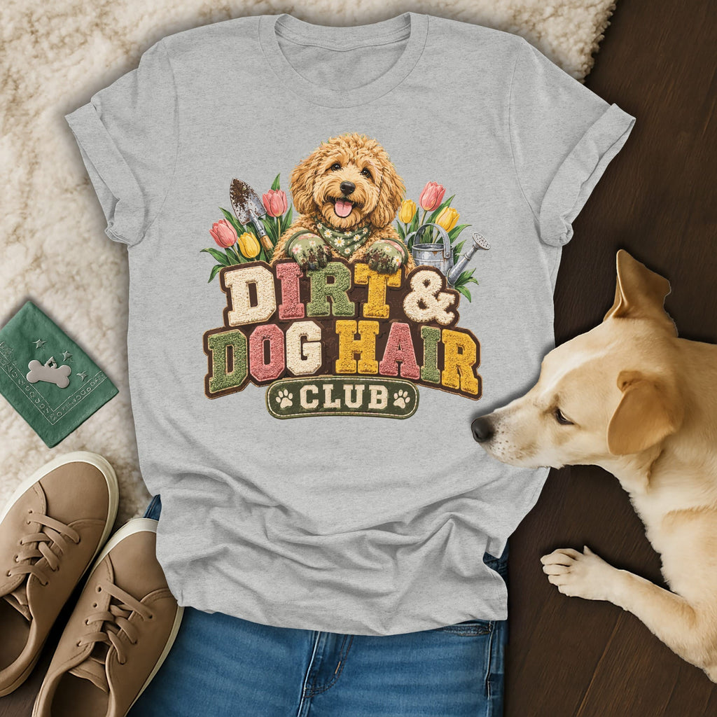 Gray t-shirt featuring a graphic of a golden doodle, gardening tools, and the text Dirt and Dog Hair Club.